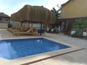 a swimming pool with chairs and a straw umbrella at Işıl Suit Apart Otel in Dalyan