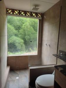 a bathroom with a toilet and a large window at mountain cabin for bird watching in Sabaneta
