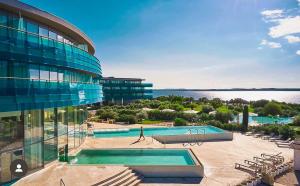 a building with a swimming pool next to a body of water at Premium Apartment Falkensteiner in Petrcane