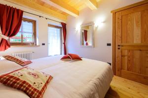 Un dormitorio con una gran cama blanca y una ventana en Baite Rosa, en Alagna Valsesia