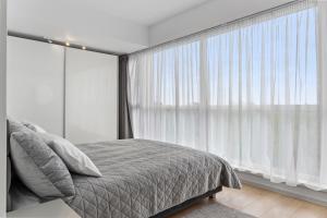 a bedroom with a bed and a large window at Atria Urban Gateway, 2BR Condo + Pool in Bucharest +19 photos