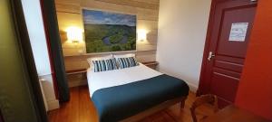 a small bed in a room with a painting on the wall at Logis hôtels Auberge du Château in Saint-Rémy-de-Blot