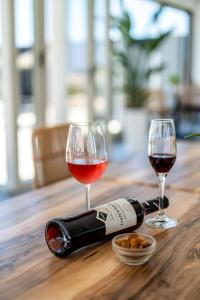 two glasses of wine and a bottle on a wooden table at En Plo Boutique Suites in Oia