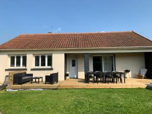 une maison avec des chaises et des tables noires sur une terrasse dans l'établissement Maison de vacances normande entre Cabourg et Caen, à Troarn