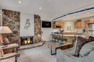 斯諾馬斯村的住宿－Laurelwood Condominiums 303，一间带石头壁炉的客厅和一间厨房