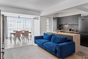 a living room with a blue couch and a kitchen at Atria Urban Gateway, 2BR Condo + Pool in Bucharest