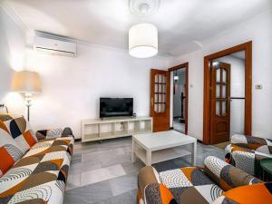 a living room with couches and a flat screen tv at Casa Limonero con parking gratis junto a centro histórico in Granada