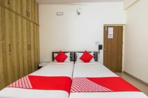1 dormitorio con 2 almohadas rojas en una cama en OYO Flagship 69694 Sagar Comforts, en Yelahanka