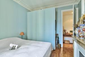 - une chambre avec un lit blanc et un mur bleu dans l'établissement Charming apartment near the Eiffel Tower - Welkeys, à Paris