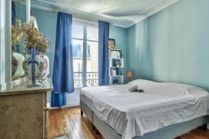 - une chambre avec un lit aux murs bleus et une fenêtre dans l'établissement Charming apartment near the Eiffel Tower - Welkeys, à Paris