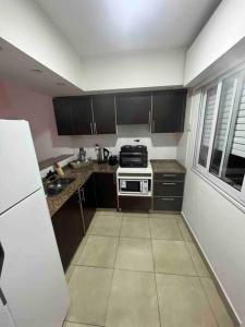 a small kitchen with black cabinets and a white appliance at Hermoso dpto en barrio camba cua in Corrientes