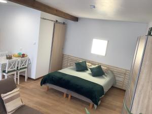 Schlafzimmer mit einem Bett mit grüner Bettwäsche und einem Tisch in der Unterkunft Studio Amis de la Moselle 