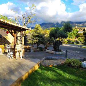 a house with a patio with a tree and mountains at Apartamentos Rurales Fuente Chiquita in Hervás