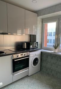 a kitchen with a stove and a washing machine at Taikos apartment in Klaipėda