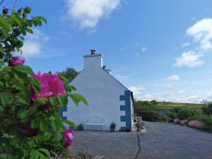 a white and blue building with a flower at New Listing - Ladybird Cottage - Donegal - Wild Atlantic Way in Donegal