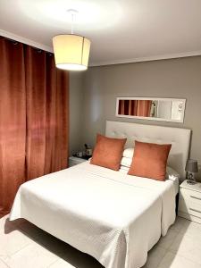 a bedroom with a large white bed with orange pillows at Hostal la Picota in Liencres