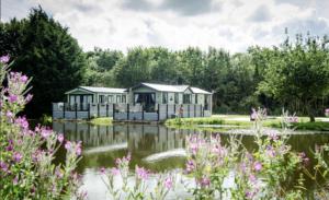 BorwickにあるBorwick Lakes Holiday Caravan (Partial Lake View)の池の隣の庭の家並み