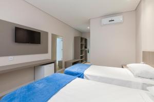 奥索里乌Tri Hotel Executive Osório的一间有两张床和一台平板电视的酒店房间