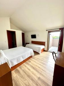 um quarto de hotel com duas camas e uma grande janela em Residencial Dona Teresa em Maia