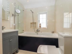 a bathroom with a tub and a toilet and a sink at Cherry Garden Cottage in Cranbrook