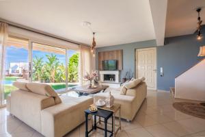 a living room with two couches and a tv at Villa Ioulia Gouves in Gouves