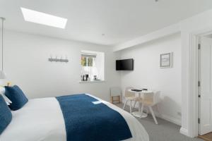 a white bedroom with a blue and white bed and a table at The Old Pilchard Works in Mousehole