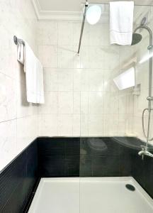 uma casa de banho com uma banheira e um chuveiro com toalhas em Residencial Dona Teresa em Maia