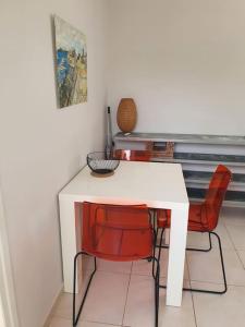 una mesa blanca con sillas rojas en una habitación en Haut de maison 5 min de la plage, en Vallauris
