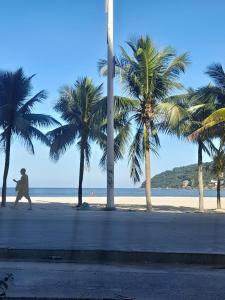 a man walking on a beach with palm trees at Eco hostel 013 in São Vicente