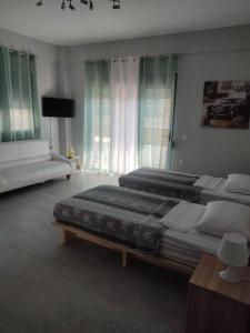 1 dormitorio grande con 2 camas y sofá en Margaritas Apartments en Sarandë