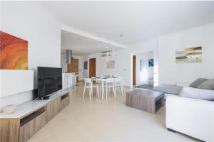 ein Wohnzimmer mit einem Sofa und einem TV in der Unterkunft LUX Seaview & Pool-Hosted by Sweetstay in Mellieħa