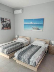 2 camas en un dormitorio con una pintura en la pared en Margaritas Apartments en Sarandë