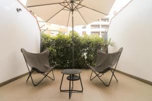 2 sillas, mesa y sombrilla en el balcón en Spectacular 1BR in Miraflores, en Lima