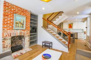 a living room with a brick fireplace and a staircase at Gertie Downtown in Charleston