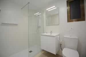 a white bathroom with a toilet and a glass shower at Apartamentos familiares Sa Gavina Gaudí in L'Estartit