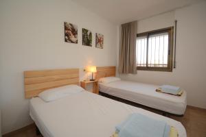 a hotel room with two beds and a window at Alojamientos familiares Sa Gavina Estartit, Principal in L'Estartit