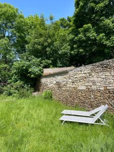 a white chair sitting in the grass next to a stone wall at CHARMING APARTMENT WITH THE PRIVATE GARDEN in Orsay