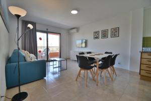 een woonkamer met een blauwe bank en een tafel en stoelen bij Apartamentos familiares Sa Gavina Gaudí in L'Estartit