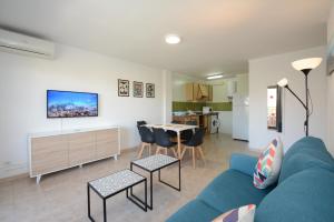 een woonkamer met een blauwe bank en een tafel bij Apartamentos familiares Sa Gavina Gaudí in L'Estartit