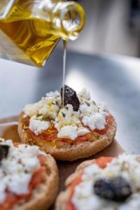 una persona está echando queso en tres pizzas pequeñas en Batelo - Adults Only, en Benitses