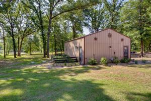 a barn with a bench in a field with trees at Dock and Fire Pit Lake Tawakoni Vacation Rental! in Wills Point