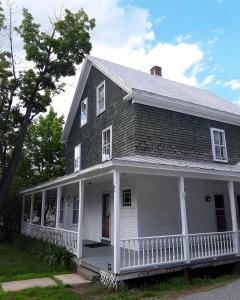 an old white house with a white porch at Terrapin Hostel in Kingfield