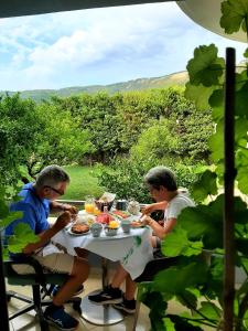 Dois homens sentados à mesa a comer. em Hotel Vila Arbri em Berat