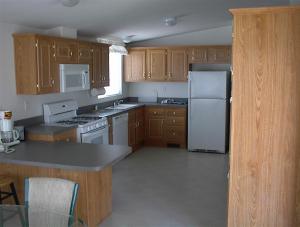 a kitchen with wooden cabinets and a white refrigerator at Waterfront Colorado River Home With Private Dock! in Needles