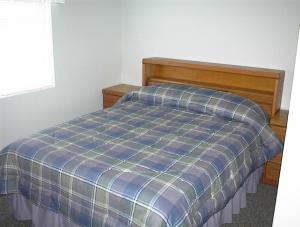 Una cama en un dormitorio con una manta de cuadros azul en Waterfront Colorado River Home With Private Dock!, en Needles