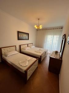una camera da letto con due letti e un lampadario di Amal Vlora Apartament a Vlorë