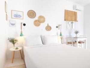 a white bedroom with a bed and a table at La Vista TINOS in Agios Ioannis Tinos