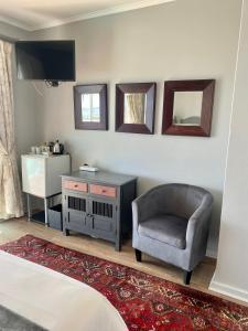 1 dormitorio con silla, escritorio y espejo en 3ColoursBlue Guest House, en Mossel Bay