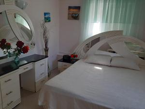 Schlafzimmer mit einem weißen Bett und einem Spiegel in der Unterkunft Cozy flat in Nea Makri in Nea Makri