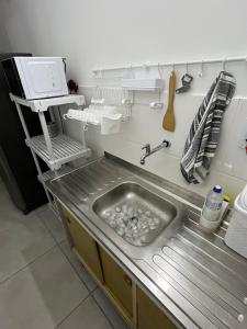 eine Küche mit einem Waschbecken in einer Küche mit einer Mikrowelle in der Unterkunft Apt Central Caraguá in Caraguatatuba